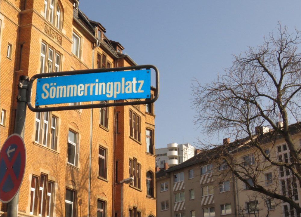 Straßenschild Sömmeringplatz mit Blick auf Häuserfront Straßenschild Sömmeringplatz mit Blick auf Häuserfront